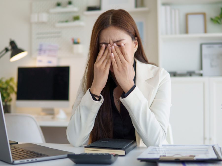 Exhausted woman rubbing her eyes at her office desk