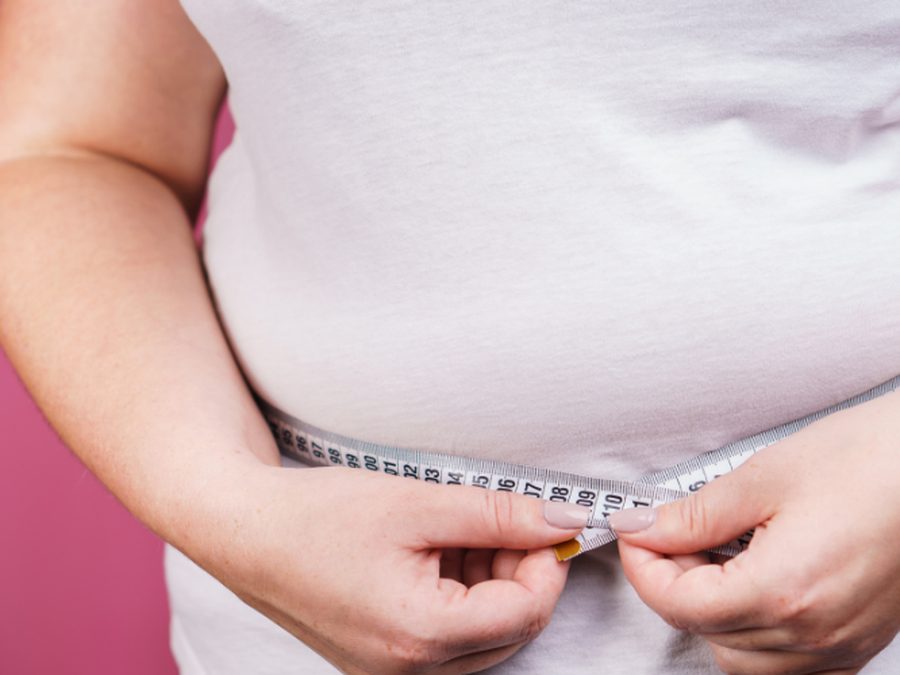 Close-up of a woman measuring her waist with a tape measure